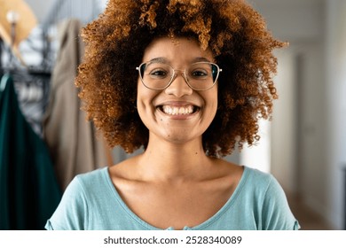 Portrait of happy biracial woman with curly hair and glasses at home. Domestic life and lifestyle, unaltered. - Powered by Shutterstock