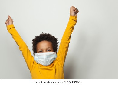 Portrait Of Happy Black Child Boy In Medical Protective Face Mask Holding Hands Up