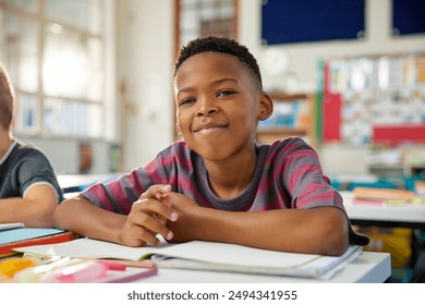 Portrait of happy black elementary boy studying in classroom while looking at camera. Close up face of little satisfied black boy writing in notebook using pencil. Proud schoolchild in primary school. - Powered by Shutterstock