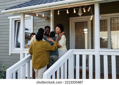 Portrait Of Happy Black Family Embracing While Standing On Porch Of New House, Copy Space