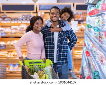 Portrait Of Happy Black Family Posing Together At Grocery Store. African American Parents With Cute Daughter Looking At Camera And Smiling At Shopping Mall. Satisfied Customers At Supermarket