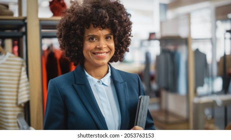 Portrait Of A Happy Black Female With Stylish Afro Hair Smiling And Posing For Camera At Clothing Store With Tablet Computer. Small Business Owner In A Role Of A Businesswoman Or Sales Manager.