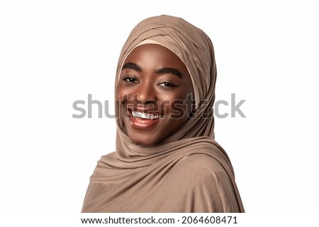 Portrait of happy black muslim lady in hijab laughing, looking and posing at camera, standing isolated over white studio background, empty space. African American lady in headscarf smiling