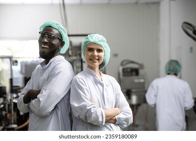 Portrait happy black worker laugh smiling together with woman friend standing arm crossed working in food and drink factory with hygiene