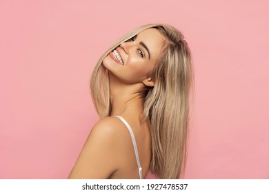 Portrait of happy blonde woman with long straight hair isolated on pastel background