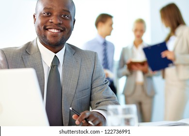 Portrait Of Happy Boss Looking At Camera In Working Environment