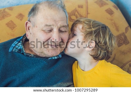 portrait of a Happy boy kissing happy granddad at home
