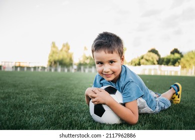 portrait of happy boy lying on football field. sports section. Training of children, child with football soccer ball on field. soccer champion. Sport concept. kid laying down - Powered by Shutterstock