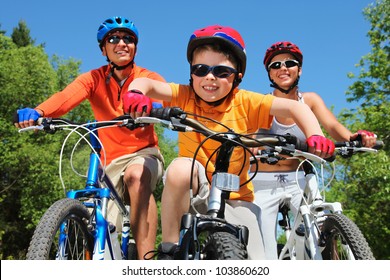 Portrait of happy boy riding bicycle in the park with his parents behind - Powered by Shutterstock