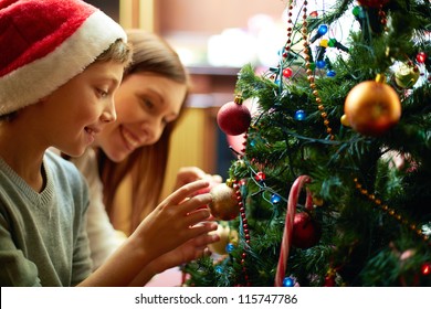 Portrait of happy boy in Santa cap decorating Christmas tree - Powered by Shutterstock