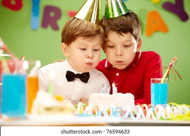 Portrait Of Happy Boys On Birthday Party Blowing At Candles On Cake