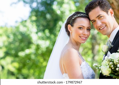 Portrait Of Happy Bride And Groom With Head To Head In Garden