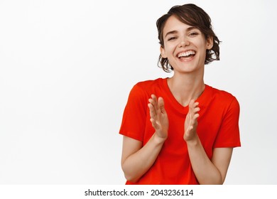 Portrait of happy brunette girl laughing, clap hands and looking pleased, applause to praise you, complimenting, standing over white background