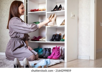 Portrait Happy Brunette Woman Hold Black Stylish Pair Of Shoes On Heels Tidying Wardrobe Closet At Home. Smiling Female With Neatly Footwear Cells Shelves Cabinet Minimalism Storage Organizer