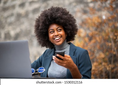 Portrait Of Happy Business Woman Sitting Outside With Laptop And Mobile Phone In Hand