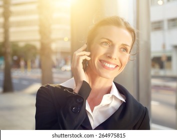 Portrait Of A Happy Business Woman Walking And Talking On Mobile Phone Outside