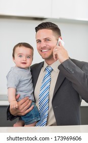 Portrait Of Happy Businessman Carrying Baby Boy While On Call At Home