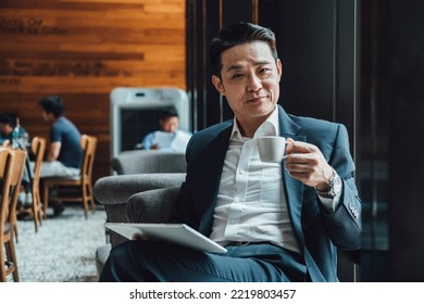 Portrait Of A Happy Businessman Drinking Cup Of Coffee And Holding His Digital Tablet In Coffee Shop - Powered by Shutterstock