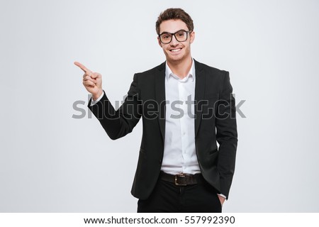 Portrait of a happy businessman in eyeglasses pointing finger away over white background