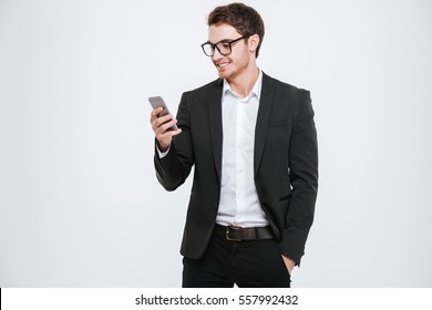 Portrait of a happy businessman in eyeglasses using smartphone over white background