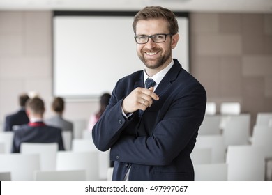 Portrait of happy businessman standing in seminar hall
