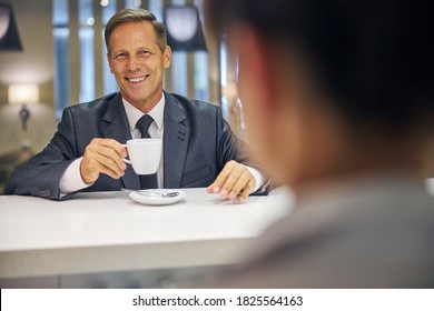 Portrait of happy businessman in suit and tie ordering cup of hot drink from barmaid - Powered by Shutterstock