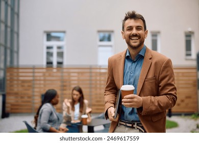 Portrait of happy businessman with takeaway coffee at office building patio looking at camera.  Copy space.  - Powered by Shutterstock