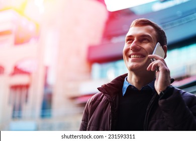 Portrait of a happy businessman walking outdoors with mobile phone. Man with phone. Happy man talking phone. Man walking with phone. Man outdoor with phone. Businessman outdoor with phone. - Powered by Shutterstock