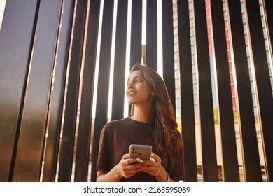Portrait of happy businesswoman standing and laughing in front of modern office - Shutterstock ID 2165595089