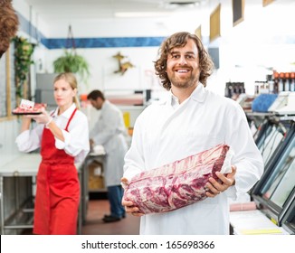 Portrait Of Happy Butcher Holding Meat Package While Standing In Store