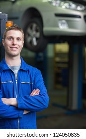 Portrait Of Happy Car Mechanic With Arms Crosses In Workshop