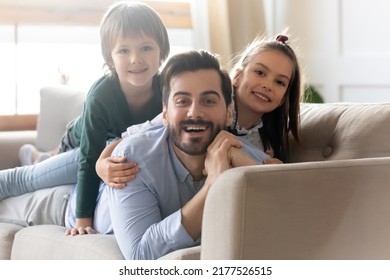 Portrait Of Happy Caring Young Father Lying On Couch Play With Two Little Kids At Home On Family Weekend. Smiling Loving Caucasian Dad Enjoy Time With Small Children, Rest On Sofa Together.