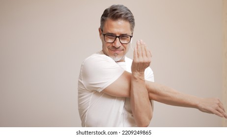 Portrait Of Happy Casual Older Man Doing Sport Activity, Training, Stretching For Workout. Mid Adult, Mature Age Guy With Gray Hair In Glasses, Isolated On White Background, Copy Space.