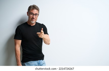 Portrait Of Happy Casual Older Man Smiling, Pointing At You. Mid Adult, Mature Age Guy At White Wall, Isolated On White Background, Copy Space.