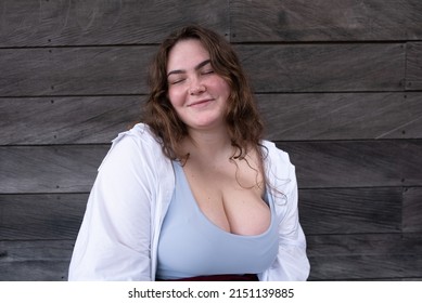 Portrait happy caucasian attractive overweight girl in white shirt smiling with closed eyes
