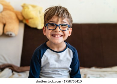 Portrait of happy caucasian boy with eyeglasses sitting at home in room in day real people small male playful child looking to the camera smiling