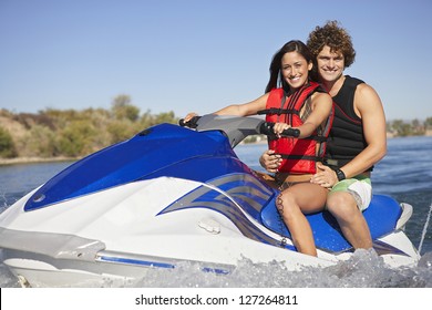 Portrait of a happy caucasian couple riding jet ski on lake