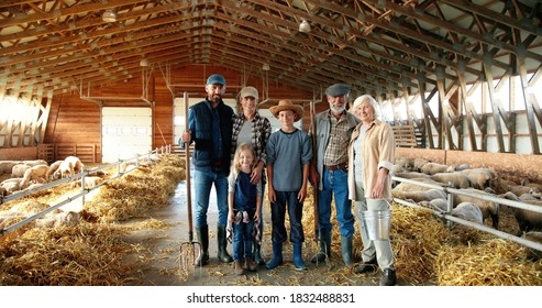 Portrait Of Happy Caucasian Family Of Three Generations Standing In Shed With Livestock And Smiling. Old Parents With Children And Grandchildren In Stable. Farmers With Kids At Farm.