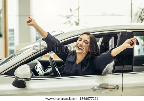 portrait of happy caucasian lady after getting new\
beautiful car, happy owner of new automobile. woman sit inside of\
car and smile