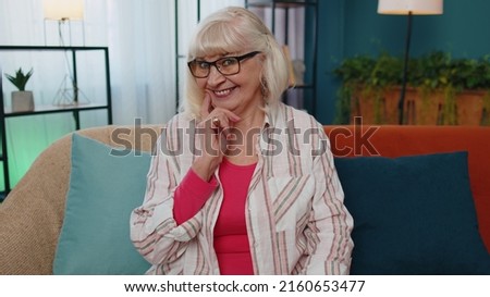 Portrait of happy caucasian senior grandmother in casual shirt smiling looking at camera. Old pretty fashion model elderly woman indoors isolated at home in living room on sofa. Female nature beauty