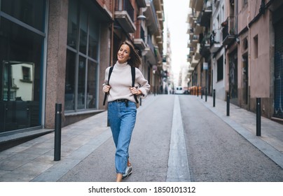 Portrait Of Happy Caucasian Woman With Backpack Walking Around Touristic City And Exploring Streets Architecture, Carefree Female Traveller 30s Visiting Town During International Vacations