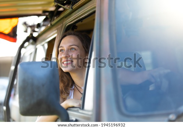 Portrait happy\
caucasian woman drives a old vintage camper van on road. Family\
travel vacation and holiday\
trip.