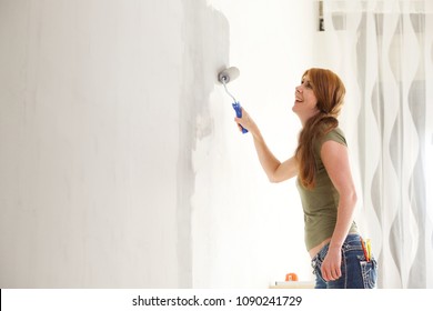 Portrait Of Happy Caucasian Woman Painting Interior Wall With Paint Roller In New House