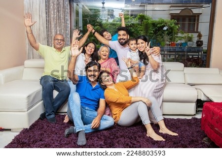 Portrait of Happy cheerful indian joint family sitting together at home. Asian senior and young couple with their kids having and laughing.