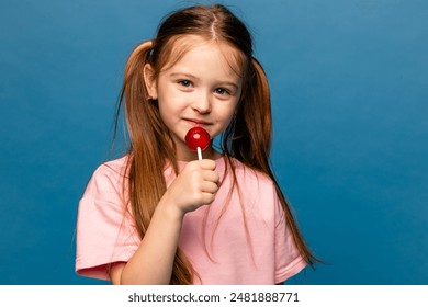 Portrait of happy cheerful little girl lick chupa-chups candy enjoy sweet snack wear good look clothes isolated over blue color background