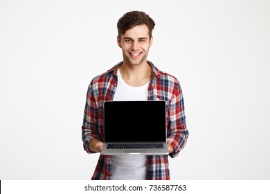 Portrait Of A Happy Cheerful Man Showing Blank Screen Laptop Computer And Looking At Camera Isolated Over White Background