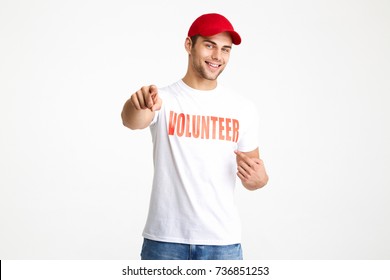 Portrait of a happy cheerful man wearing volunteer t-shirt and pointing two fingers isolated over white background