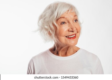 Portrait of happy, cheerful and positive old woman posing on camera alone. Amazing and beautiful smile. Close up. Wear white shirt. Stand alone. Isolated over white background