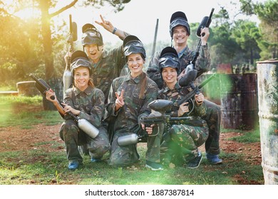 Portrait of happy cheerful smiling paintball players wearing uniform and holding guns ready for playing outdoor