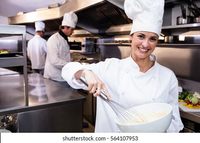 Portrait of happy chef whisking bowl of eggs in a commercial kitchen - Powered by Shutterstock